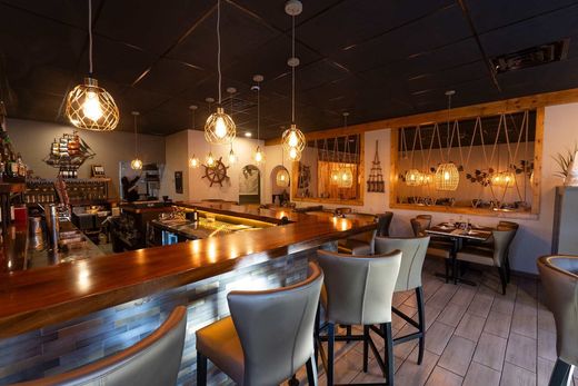 A restaurant with a long bar and tables and chairs.
