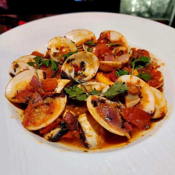 A close up of a plate of food with clams and tomatoes