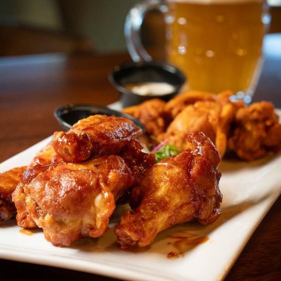 A plate of chicken wings with a glass of beer in the background