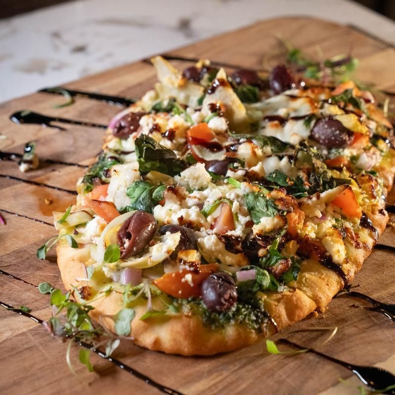 A pizza with a lot of toppings is on a wooden cutting board