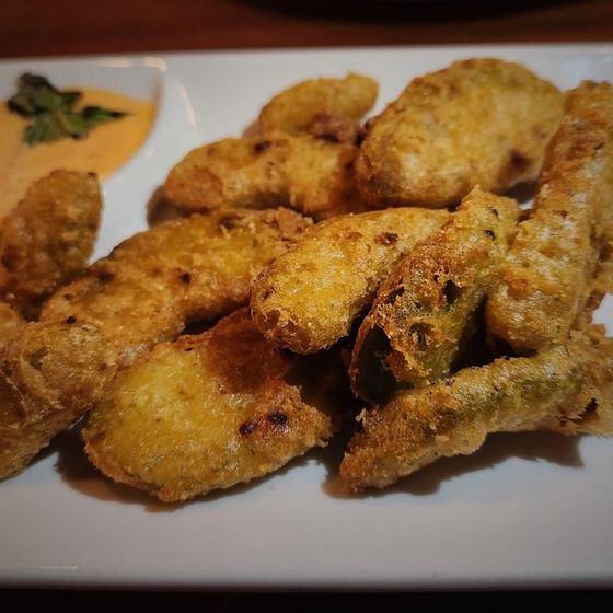 A white plate topped with fried food and a side of dipping sauce.