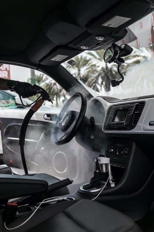 A car is being cleaned with a steam cleaner.