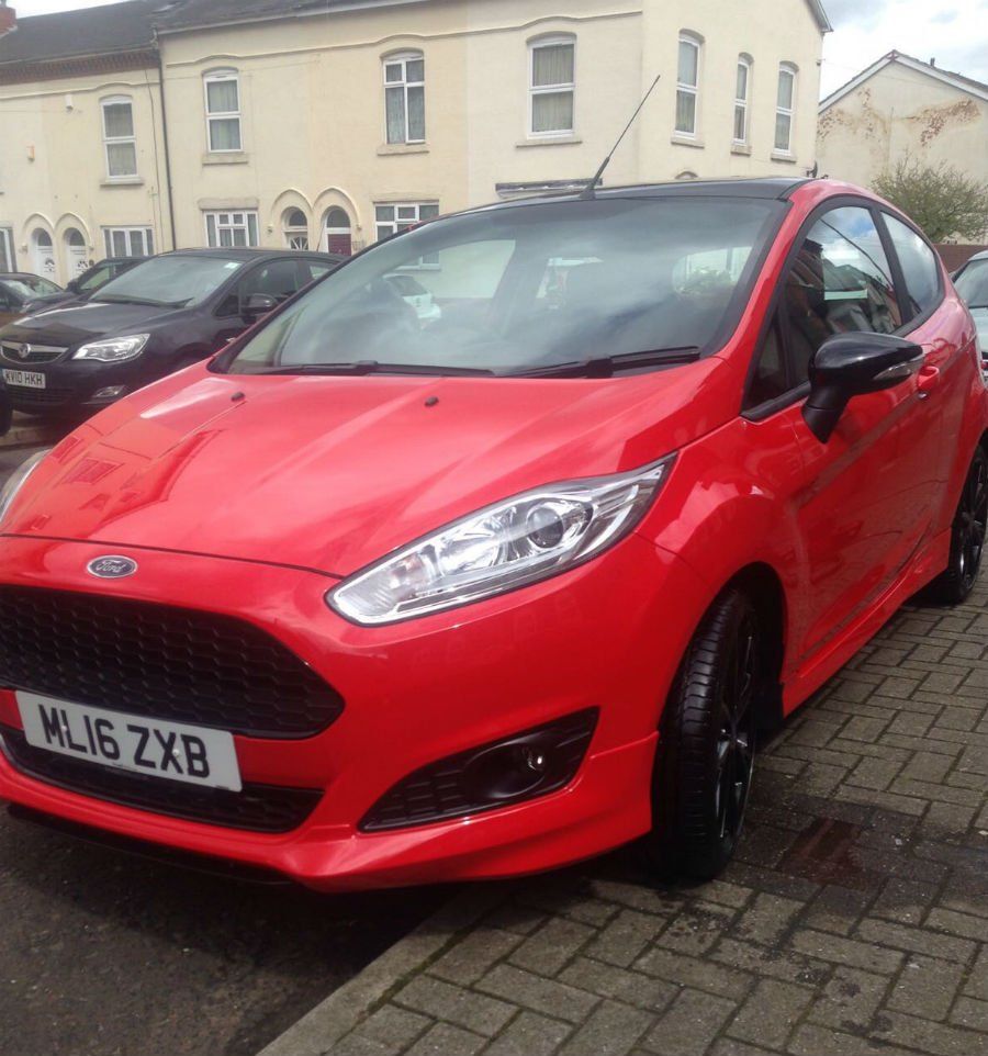 clean red car parked slightly on the kerb