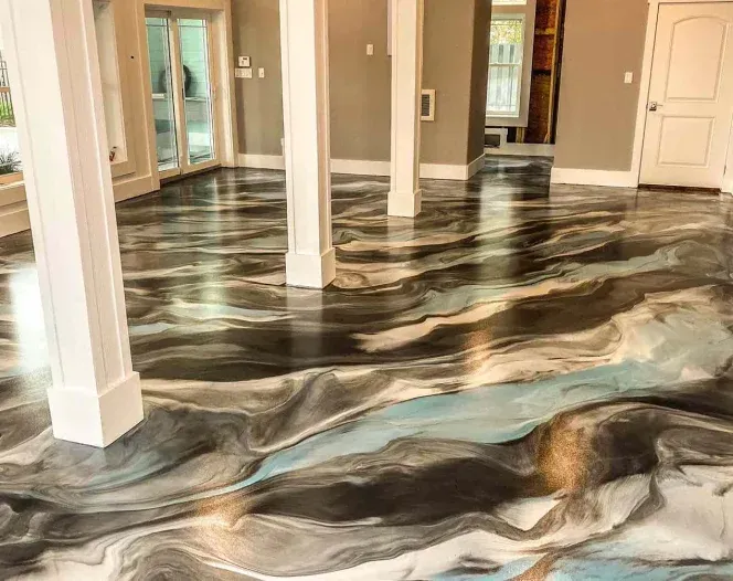 A large room with a glossy, swirled epoxy floor in shades of black, silver, blue, and white. White support columns are visible.