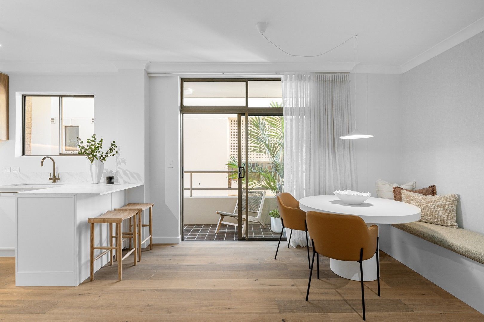 Modern dining room with white walls, built-in bench, and sliding door to balcony.