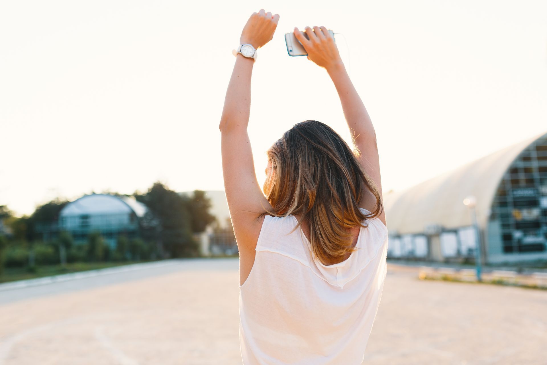 A woman is taking a picture of herself with her arms in the air.