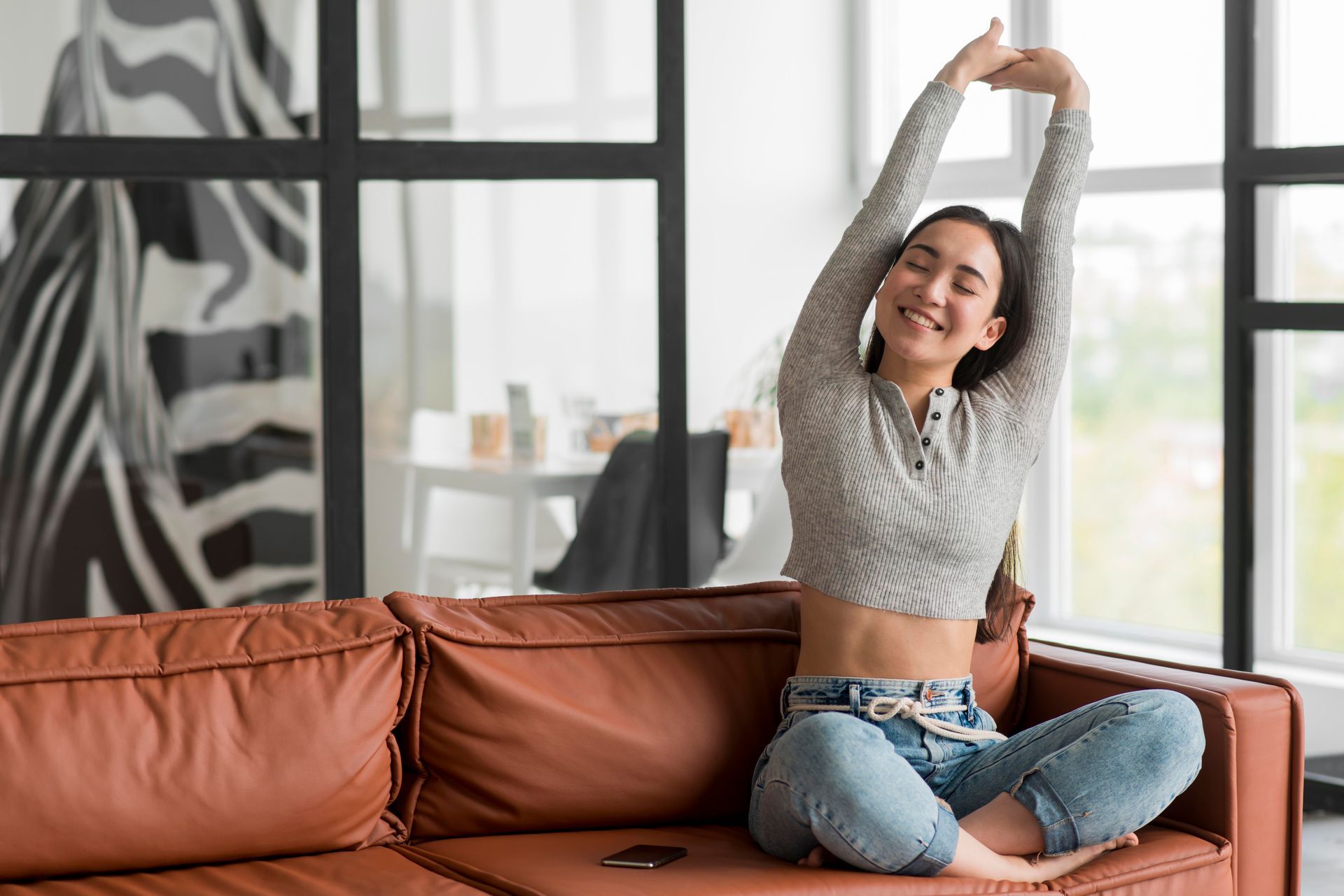 A woman is sitting on a couch stretching her arms.