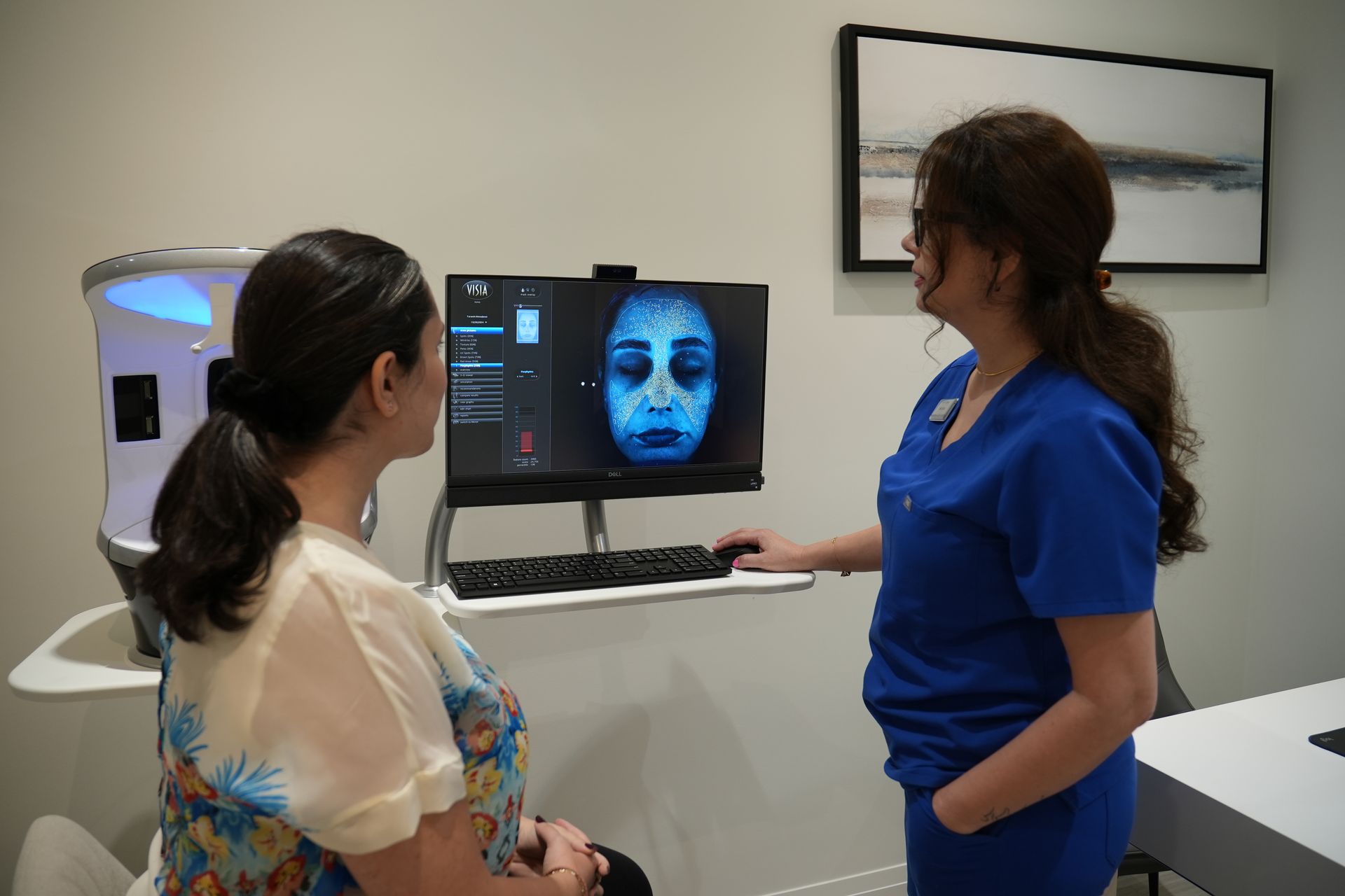 Two women are looking at a woman 's face on a computer screen.