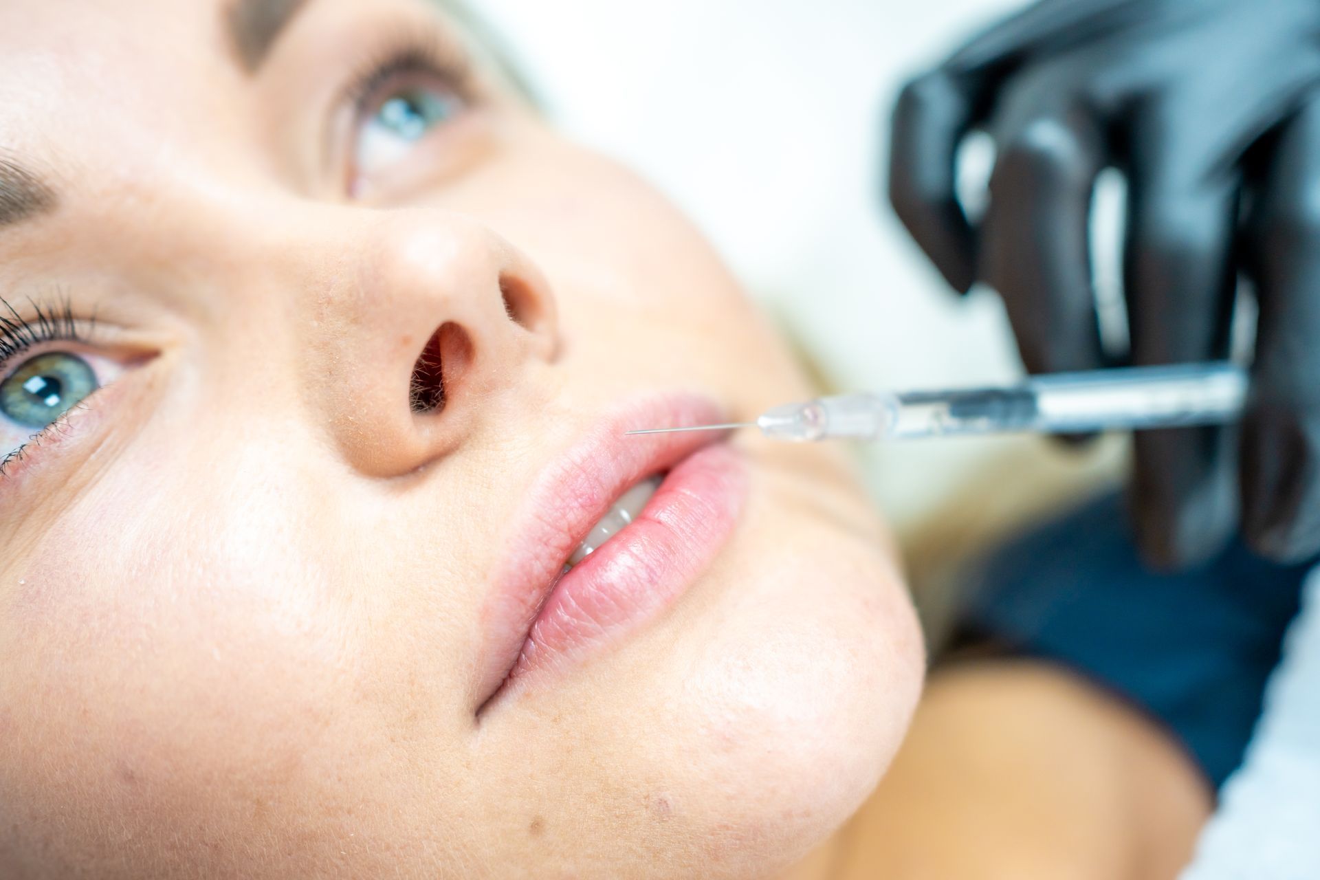 A woman is getting a botox injection in her lips.