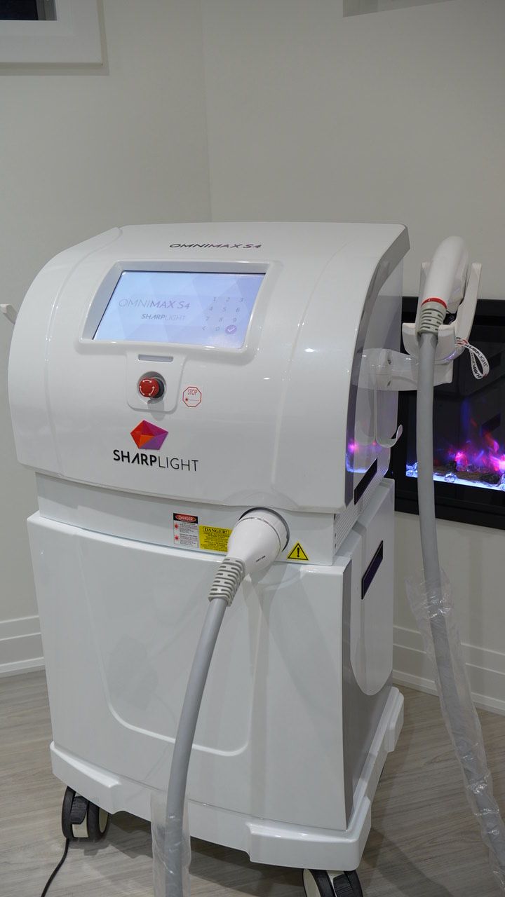 A white laser hair removal machine is sitting on a table in a room.