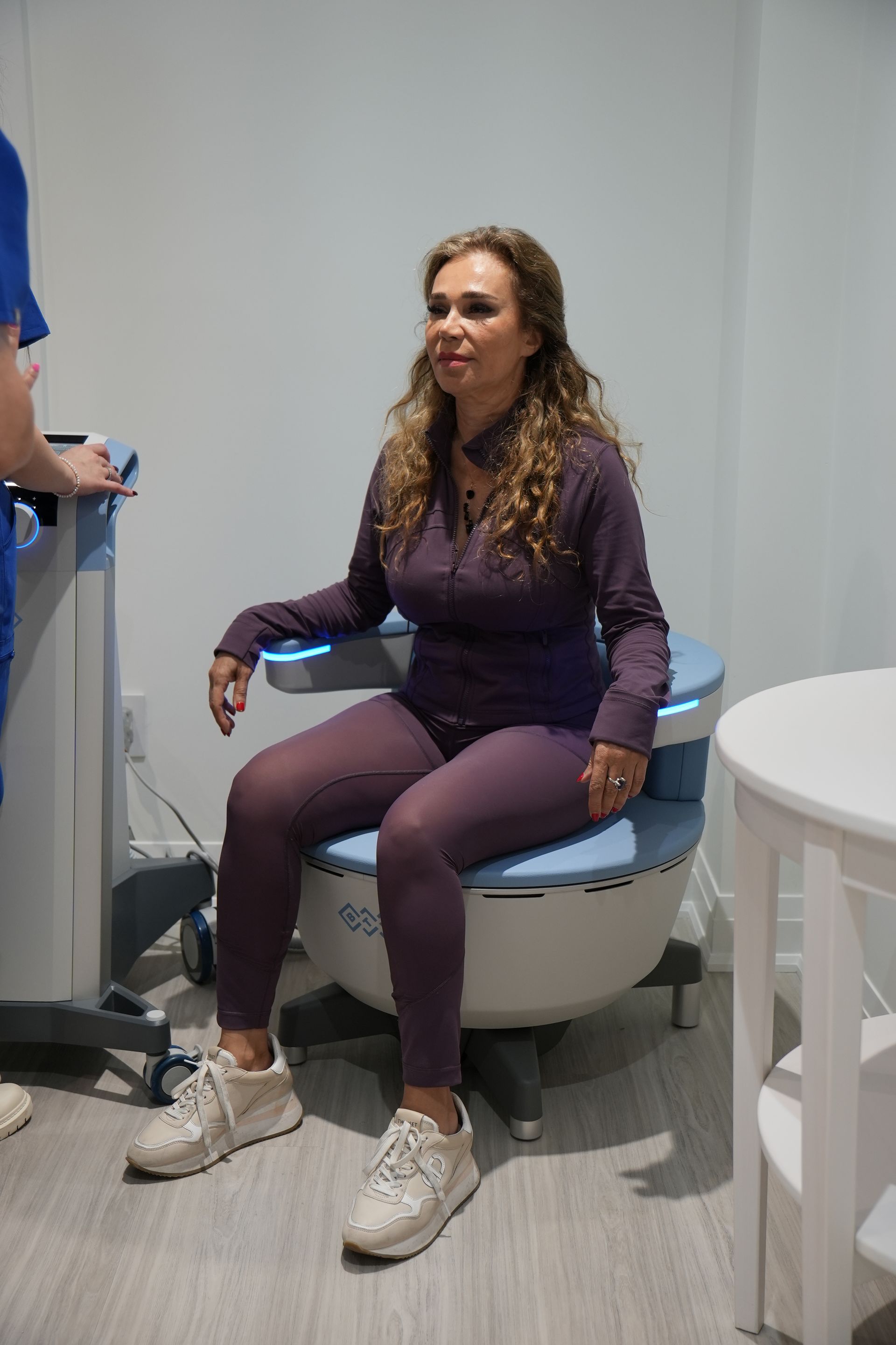 A woman is sitting on a machine in a room.