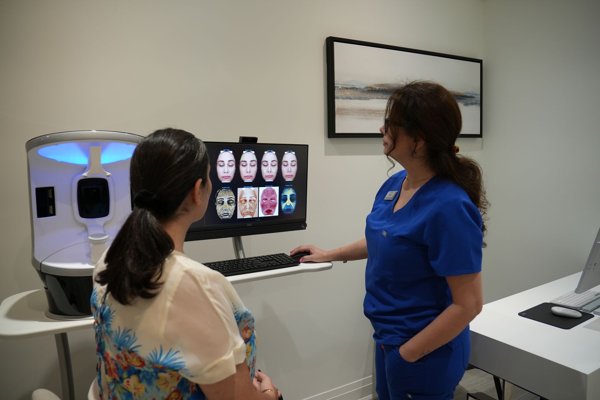 Two women are standing next to each other in front of a computer screen.