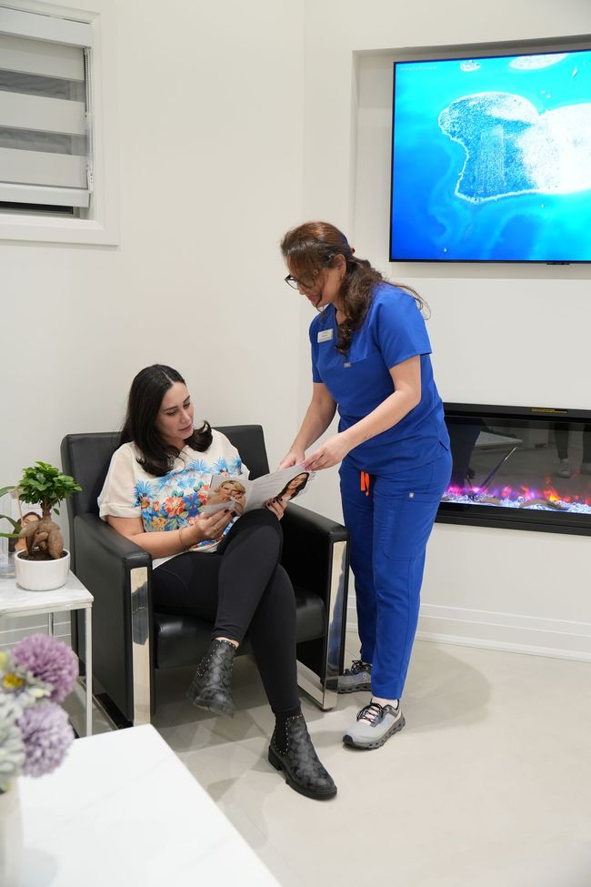 A woman is sitting in a chair while a nurse stands next to her.