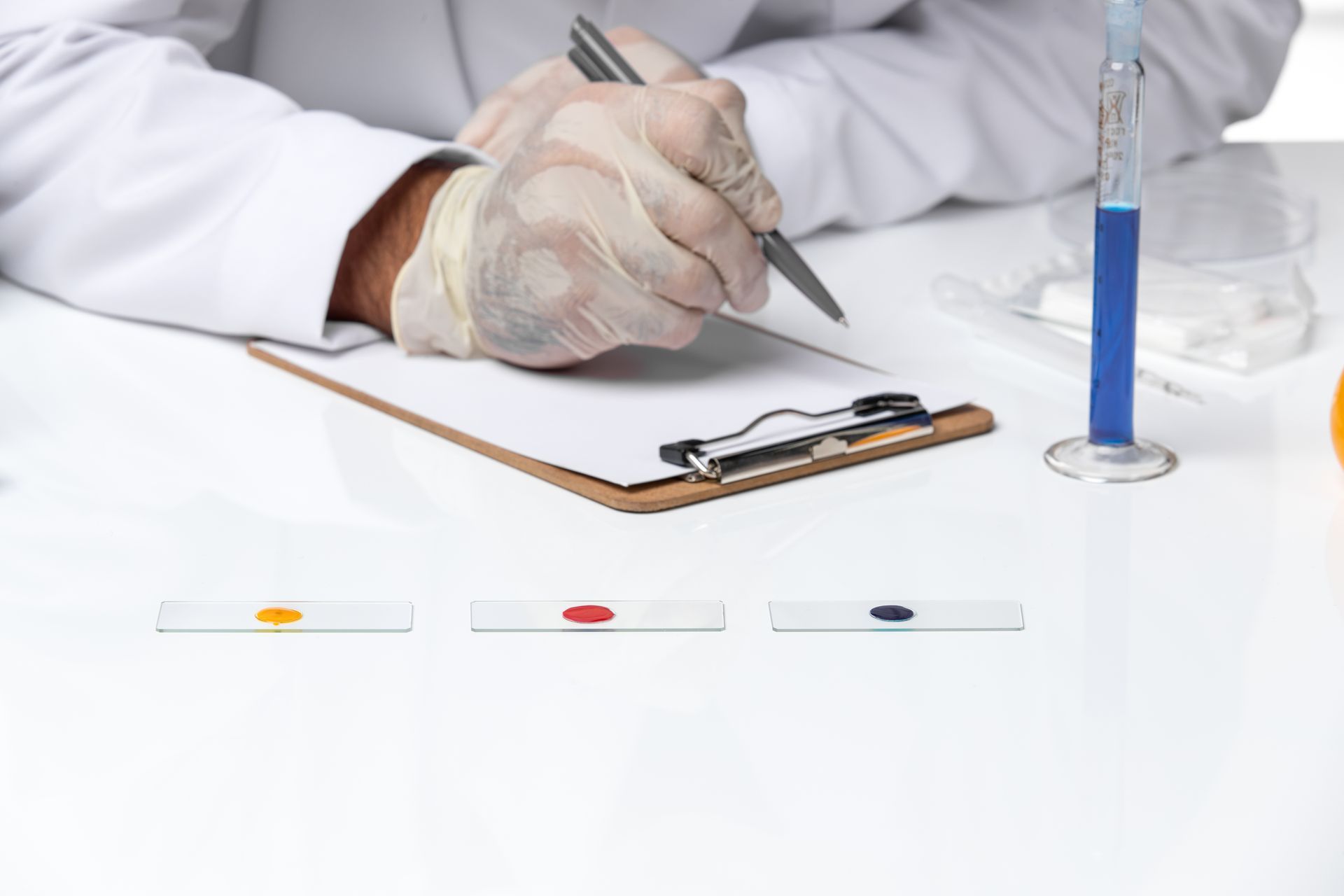 A scientist is writing on a clipboard with a pen