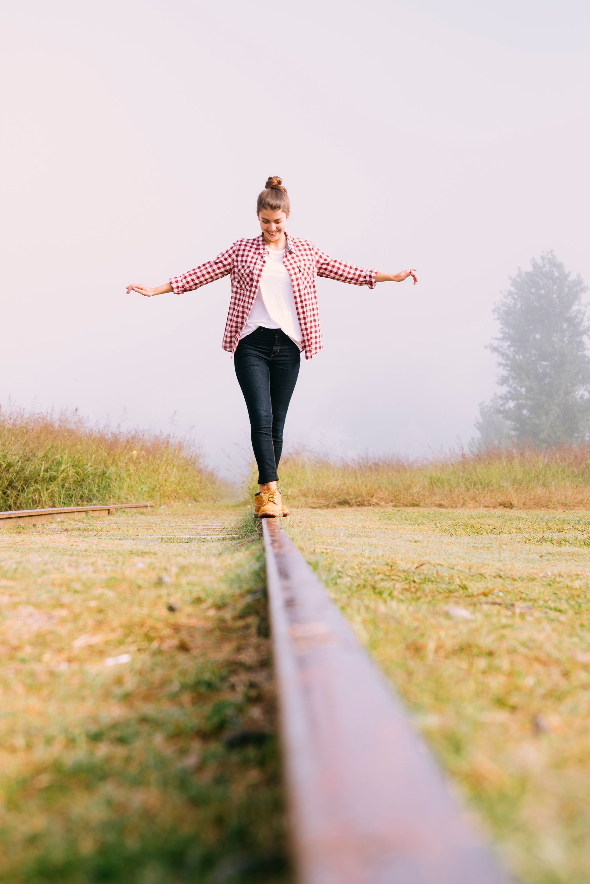 A woman is walking on a railroad track in the fog.