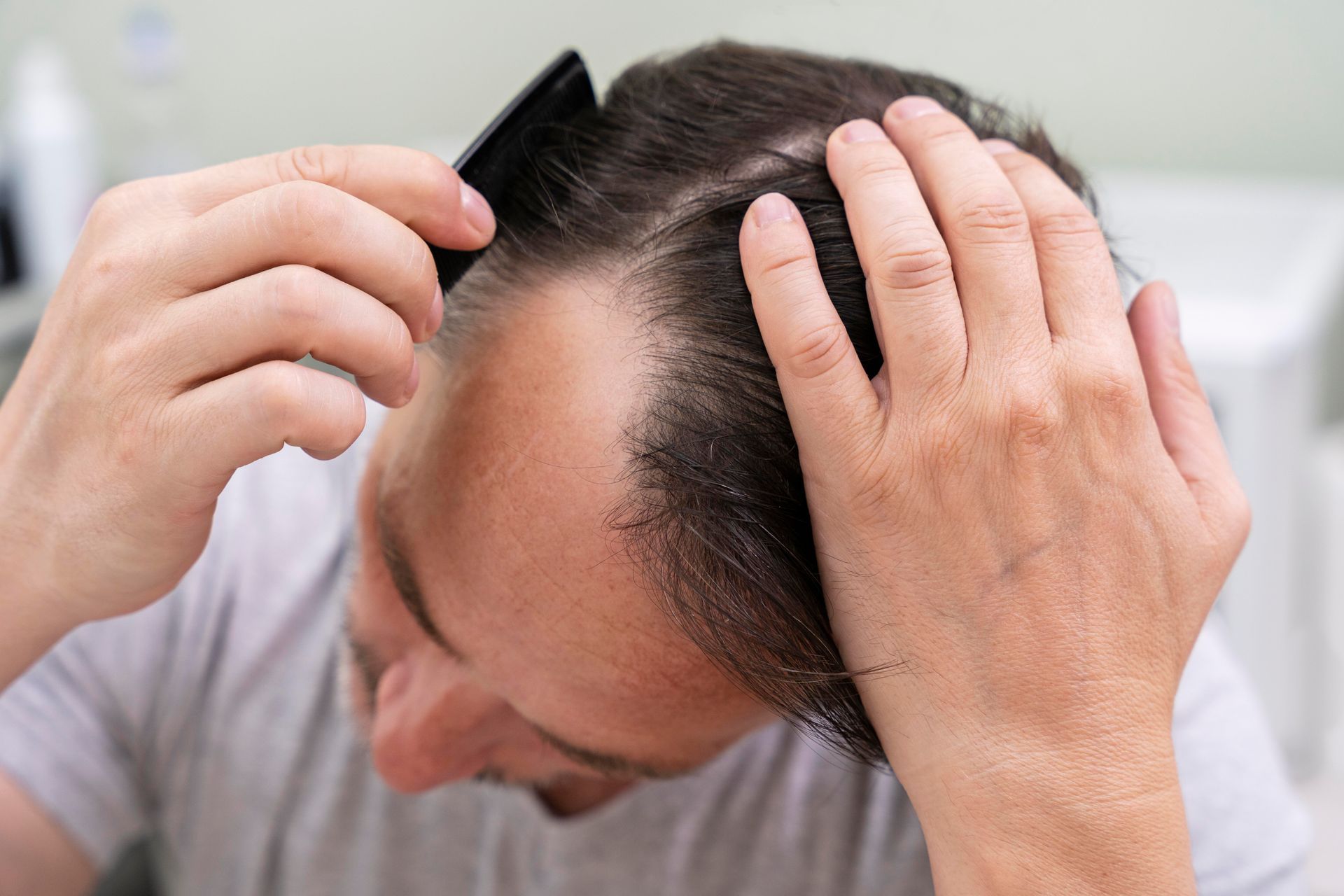 A man is combing his hair in front of a mirror.