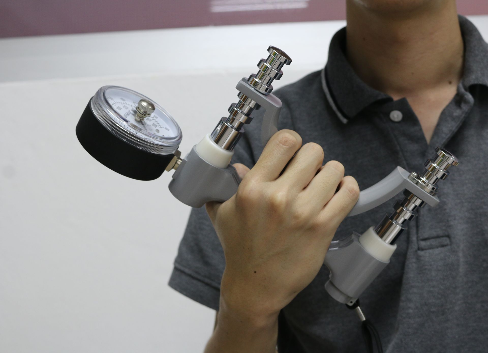 A man in a grey shirt is holding a device in his hand