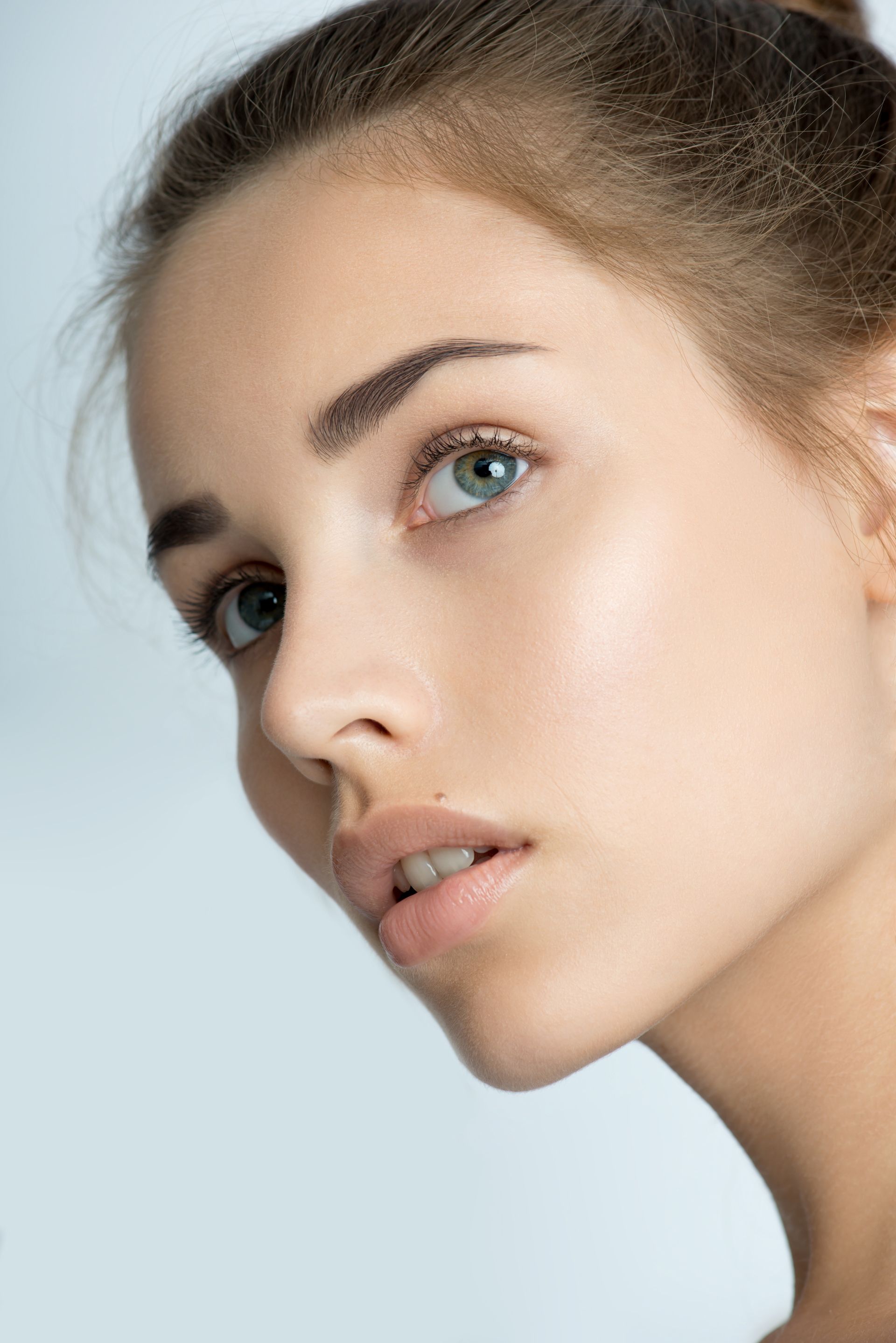 A close up of a woman 's face with her hair in a bun.