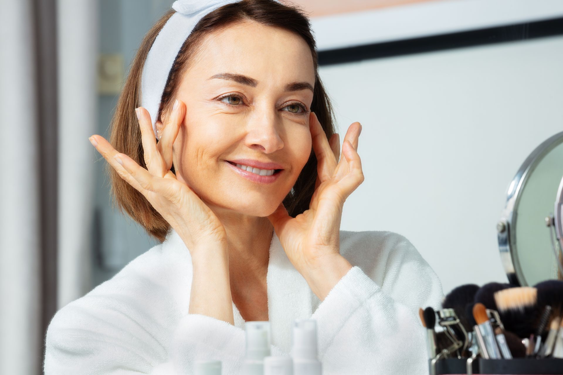 A woman is looking at her face in a mirror.