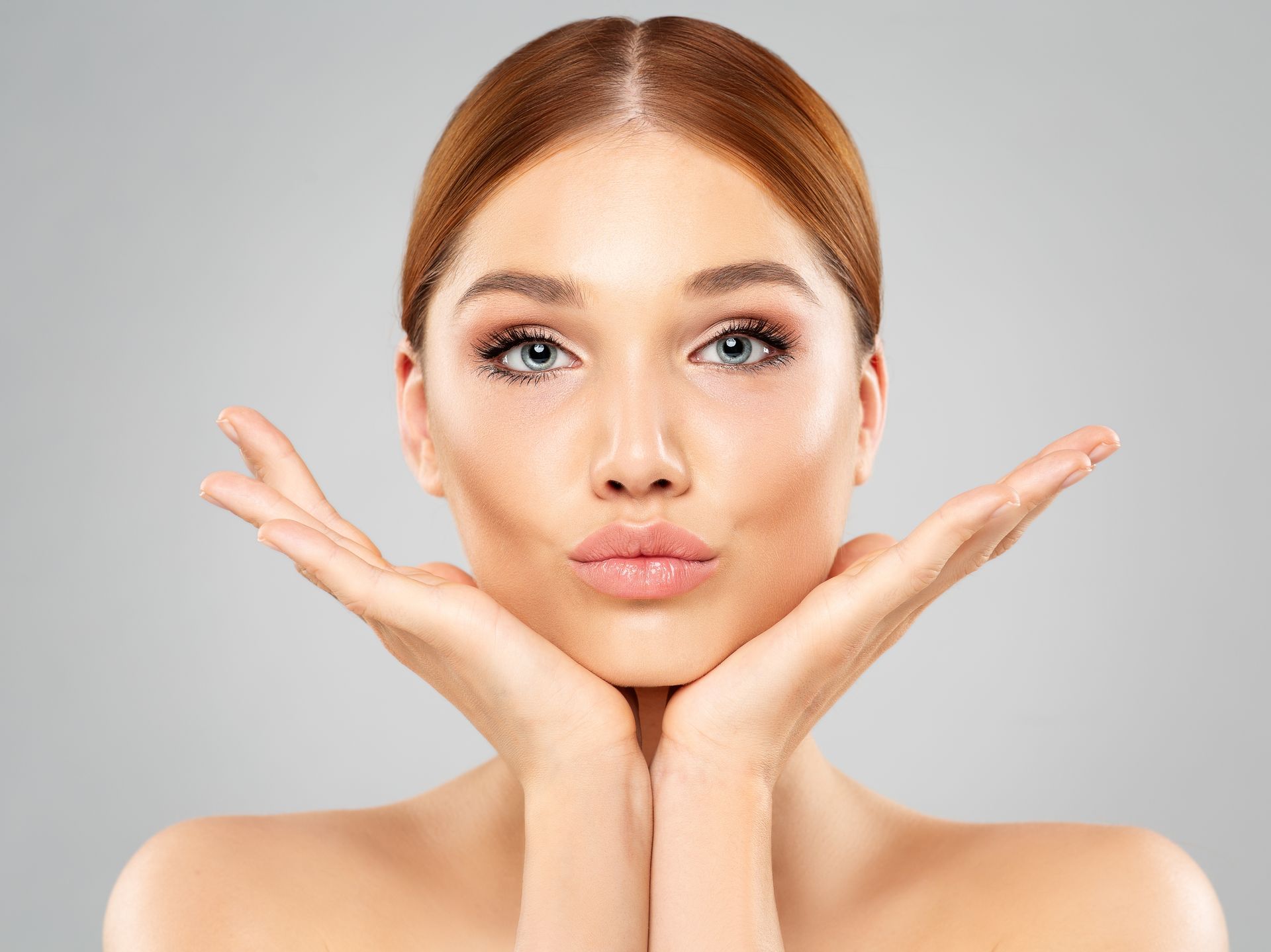 A woman is holding her face with her hands and making a funny face.