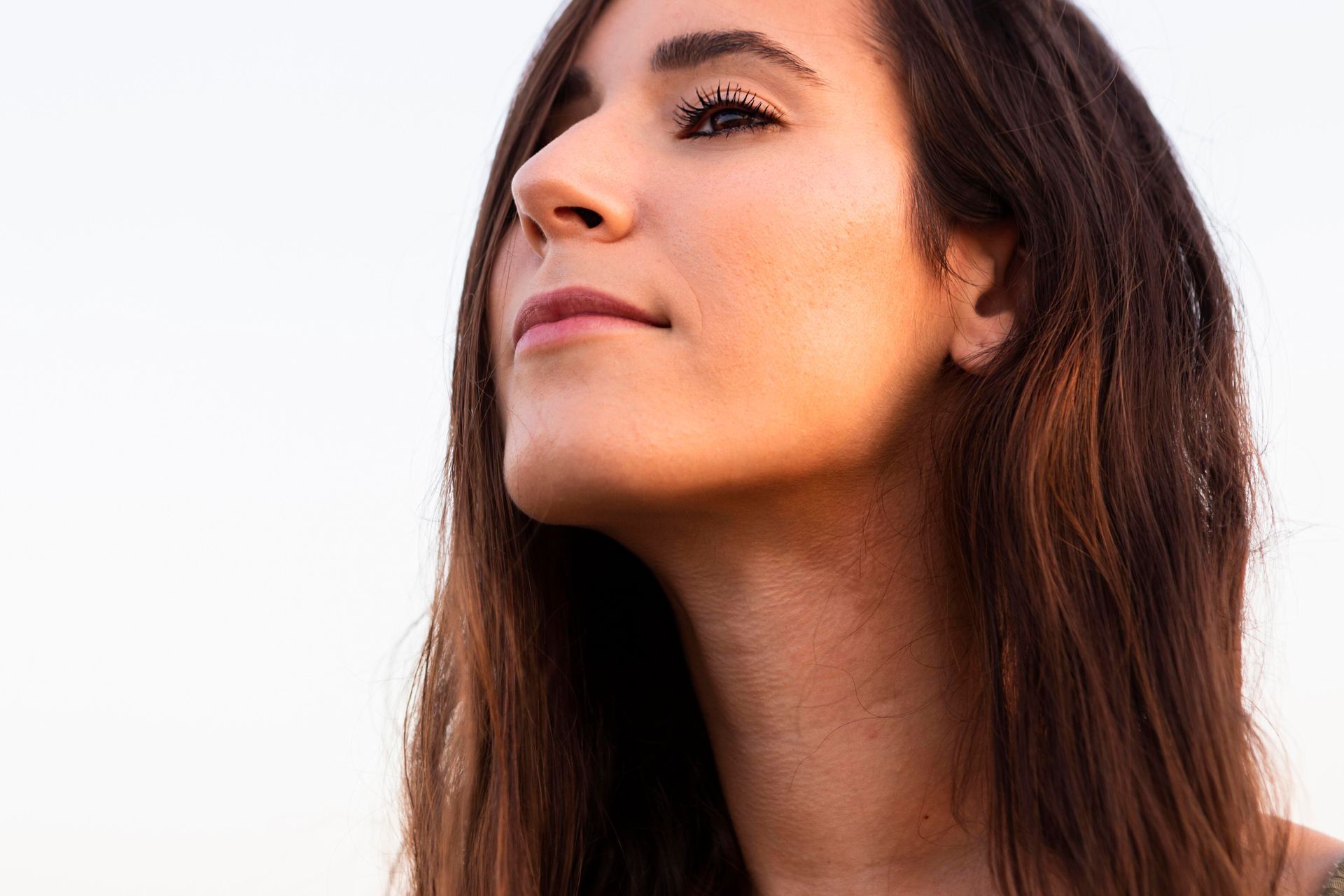 A woman with long hair is looking up at the sky.