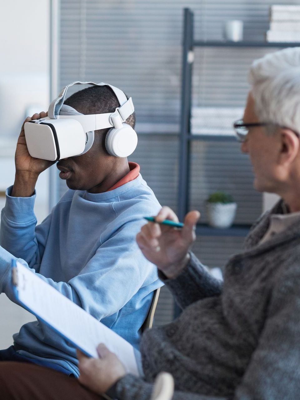 A man wearing a virtual reality headset is talking to another man.