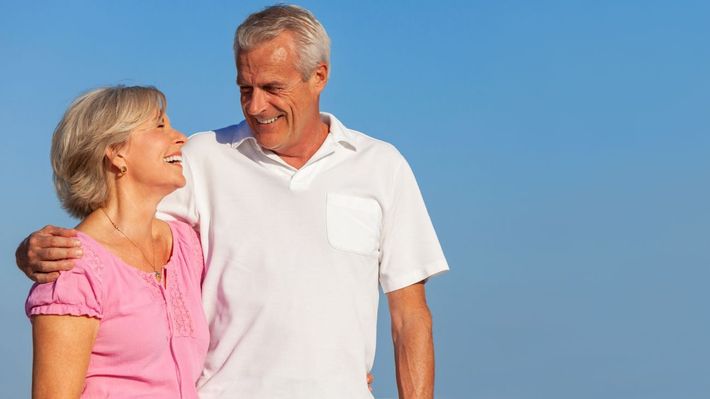 A man and a woman are standing next to each other laughing.