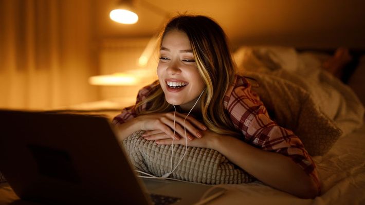 A woman is laying on a bed using a laptop computer.