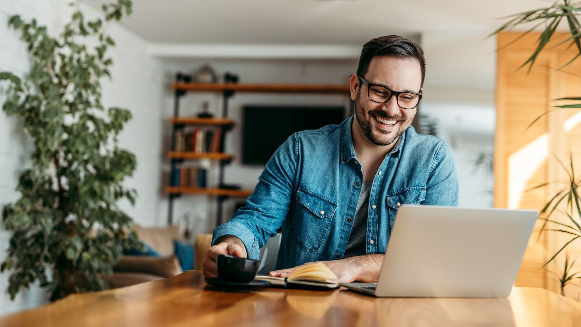 A man is sitting at a table using a laptop computer.