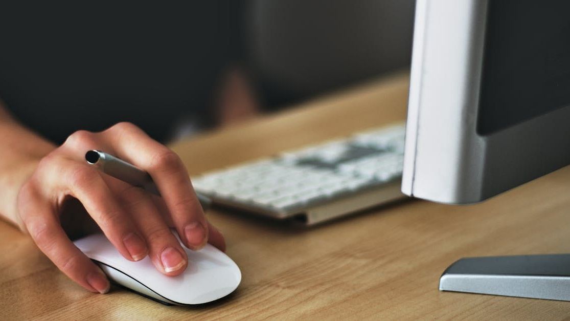 A person is using a computer mouse and writing on a keyboard.