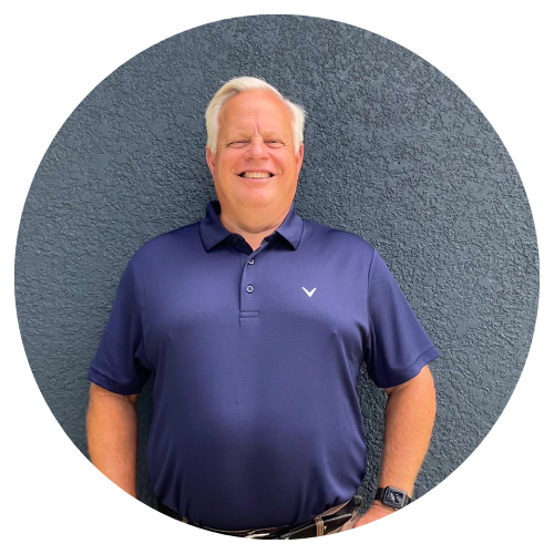 A man in a blue polo shirt is standing in front of a blue wall.