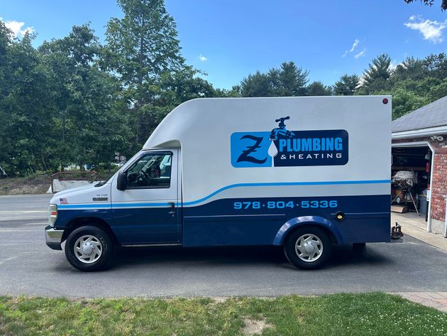 A plumbing truck is parked in front of a house