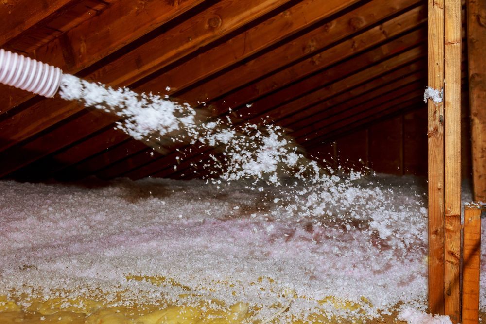 Attic being insulated with blown-in cellulose from a hose.