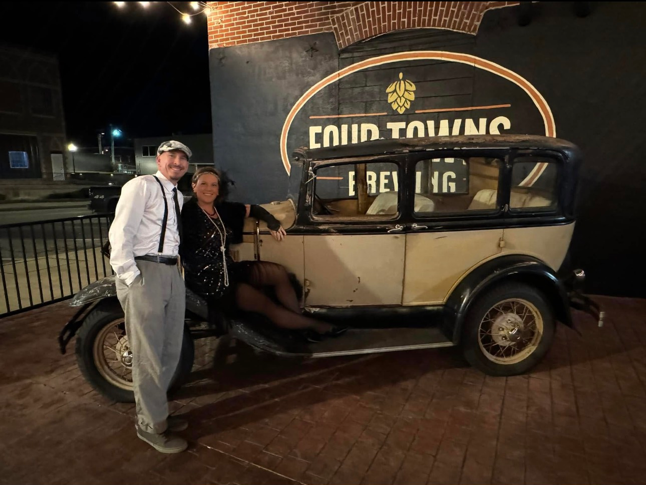 Two men are standing next to an old car.