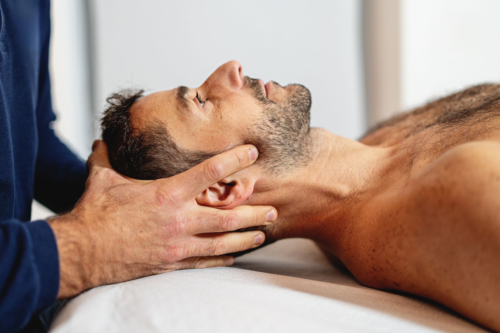 Man performing a gentle craniosacral check before starting with ArthroStim therapy for pain relief.