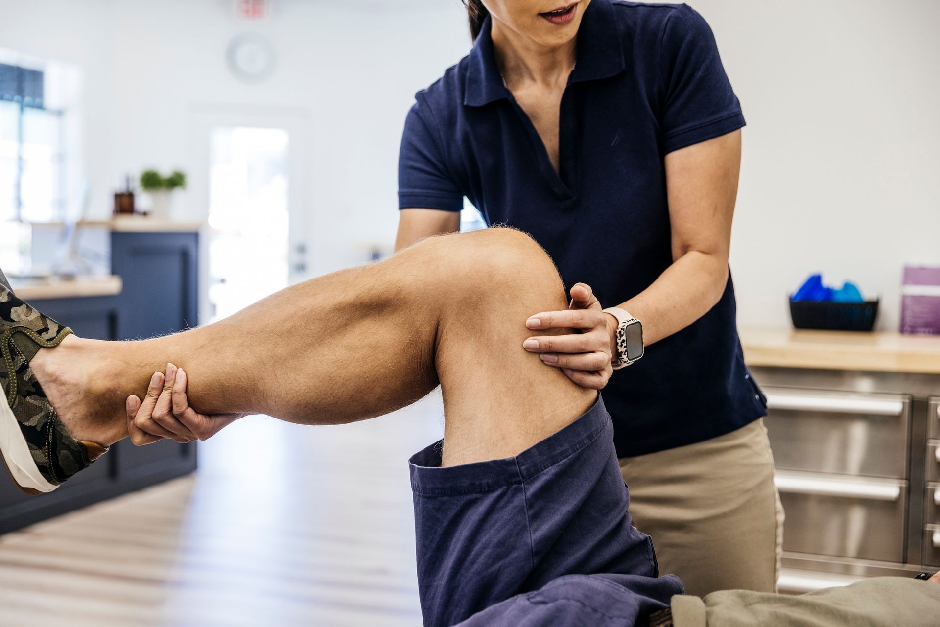 therapist stretching knee of male patient.
