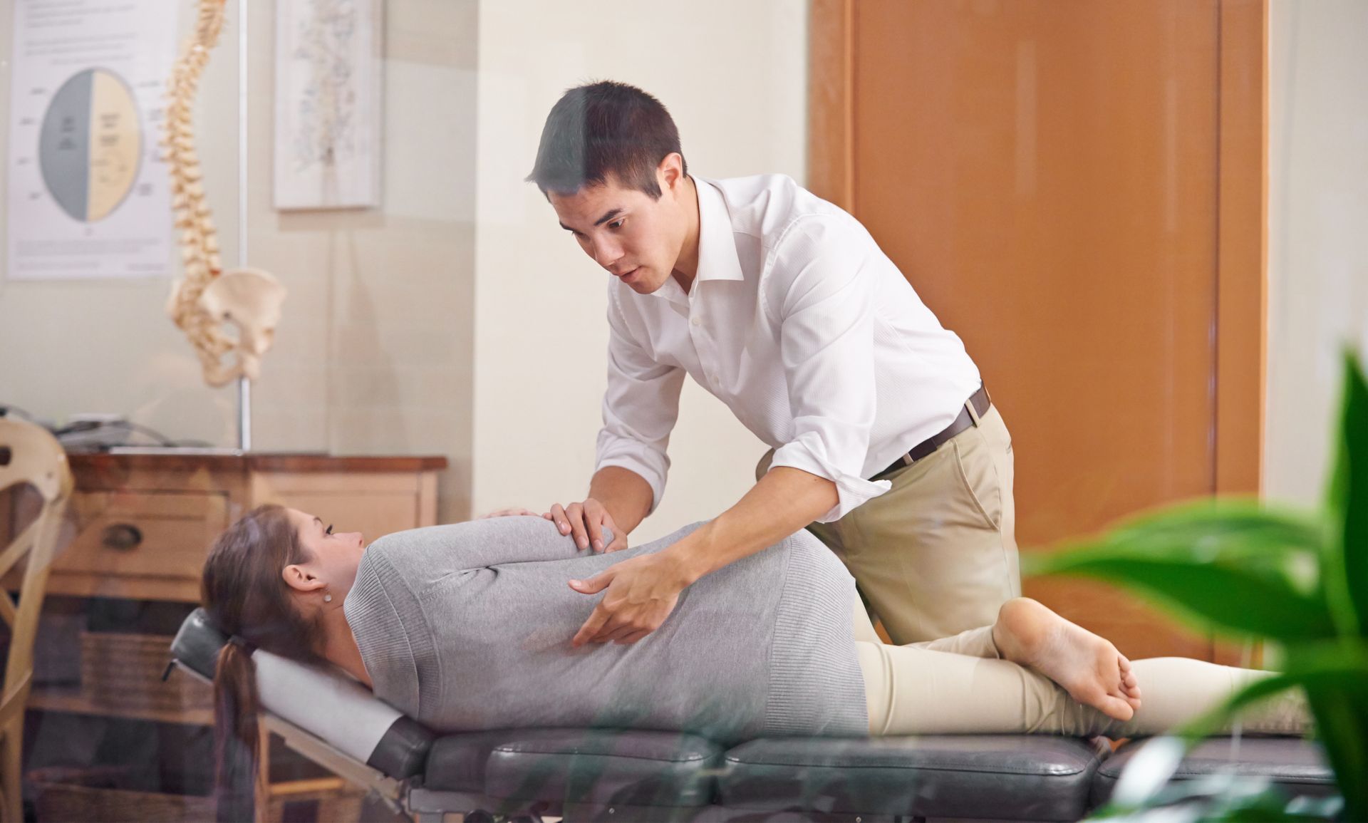 Chiropractor adjusting patient's spine on a table in a clinic.