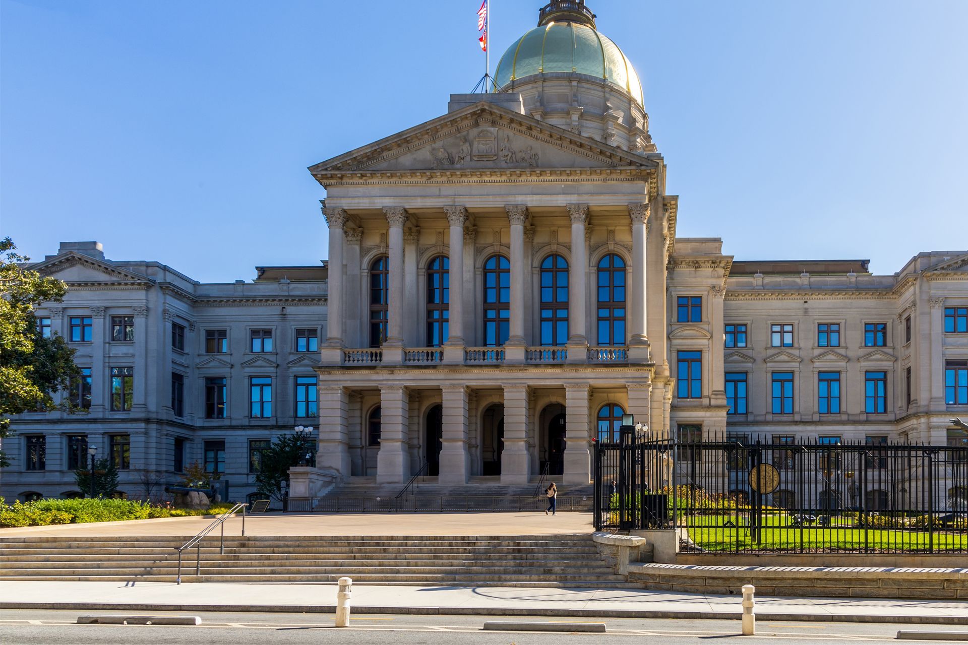Historic government building with a domed roof, grand columns, and a black iron fence in front