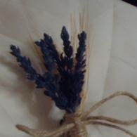 Small dried blue-purple flowers tied with tan twine on a light fabric background