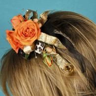 Orange rose hair clip with gold ribbon and small decorative accents in blond hair
