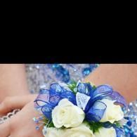 White flowers with blue ribbon on a wedding bouquet against a blurred dress background