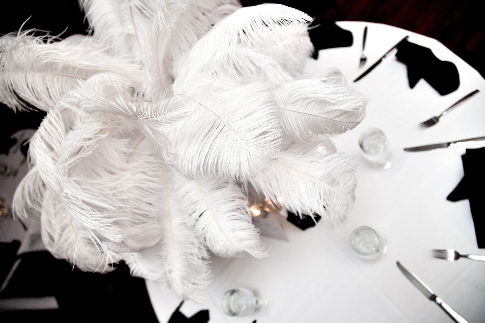 White feathered floral arrangement on a black-and-white abstract background with clear glass accents