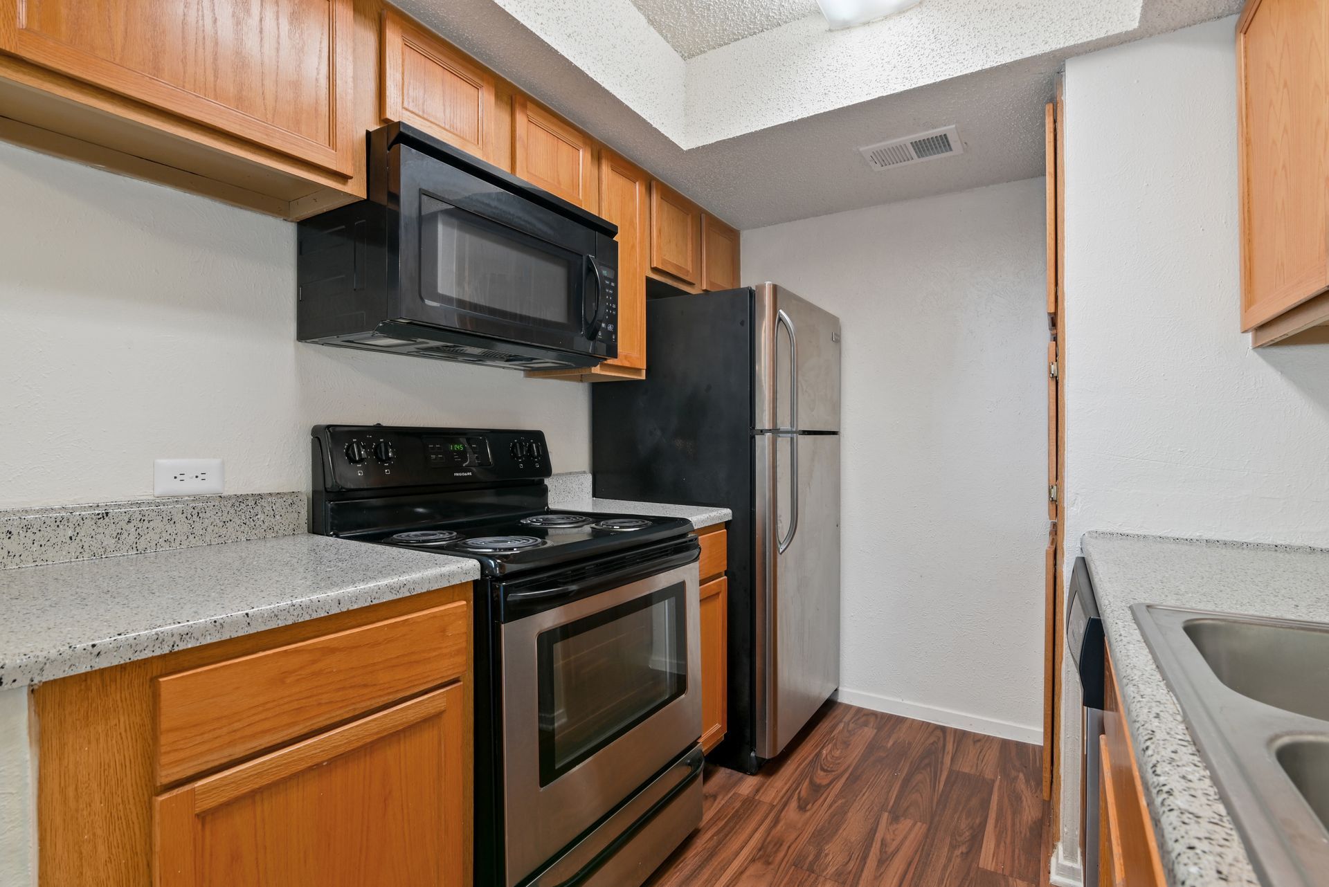 Kitchen with stainless steel appliances, wooden cabinets, and granite countertops.
