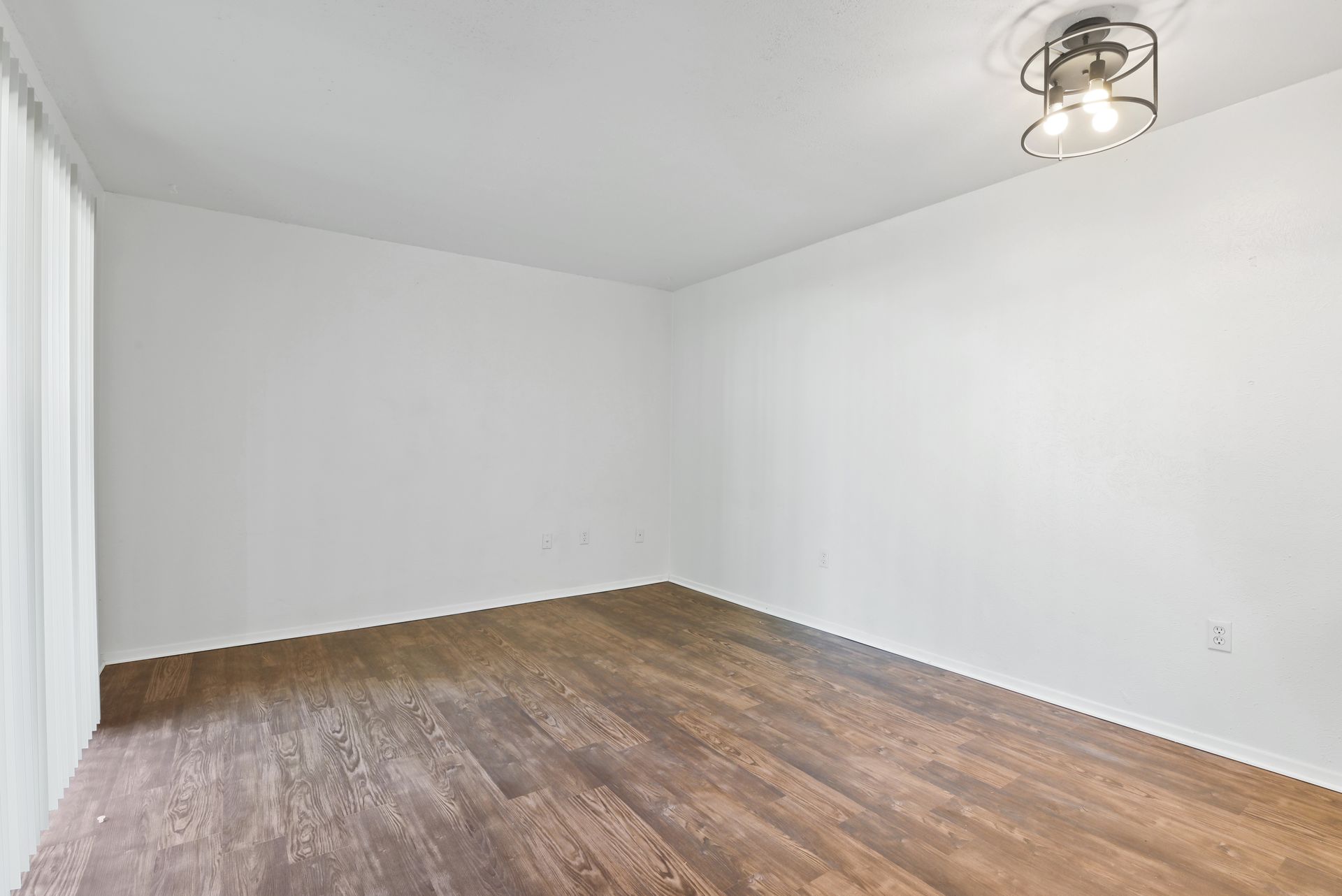 Empty apartment living space with kitchen, sliding door, and carpet.