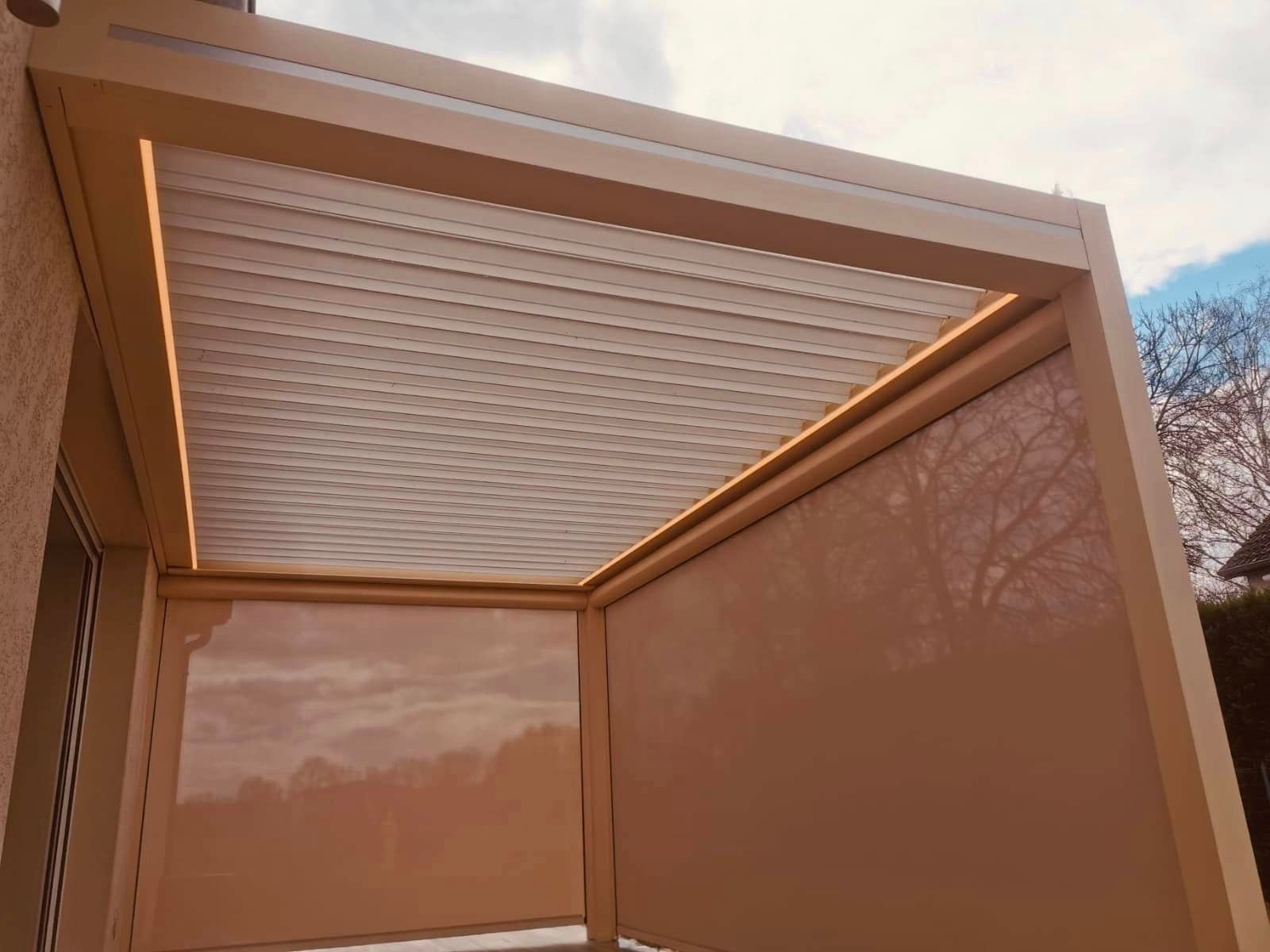 Pergola bioclimatique dans la teinte de la façade installée par TRIHOME Menuiseries à Villlegaudin