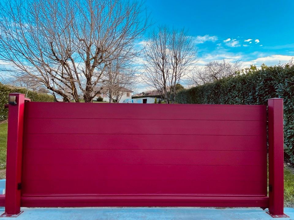 Beau portail rouge gamme Axihome installé à Cousance par TRIHOME Menuiseries, en Bresse bourguignonne