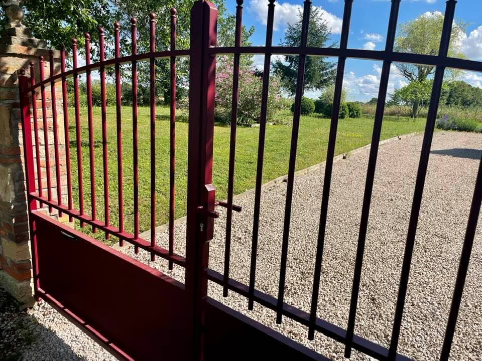 Portail teinte rouge texturé en harmonie avec l’habitation installé par TRIHOME Menuiseries à Serley