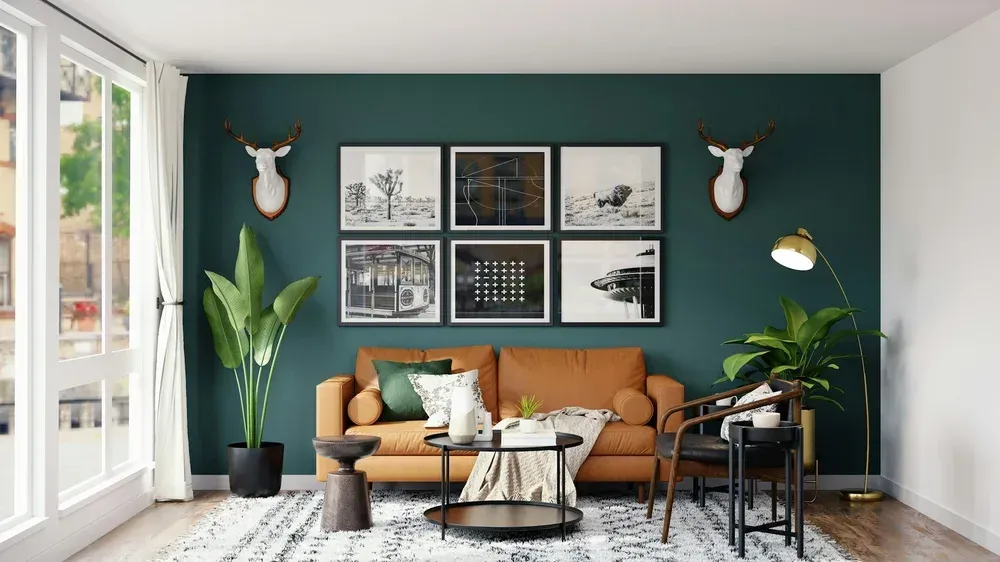 Stylish living room with teal wall, tan sofa, framed art, plants, and modern coffee table.