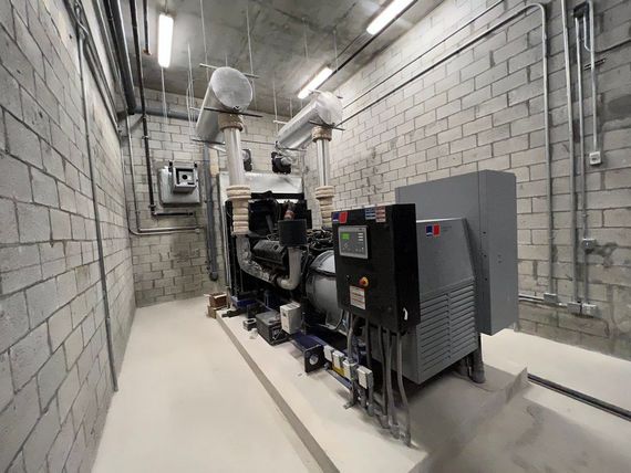 A large generator is sitting in a room with a brick wall.