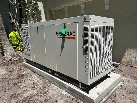 A generator is sitting in the dirt next to a building.